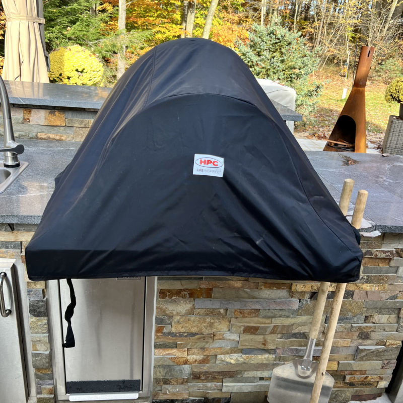 Black grill cover with HPC logo on a stone patio